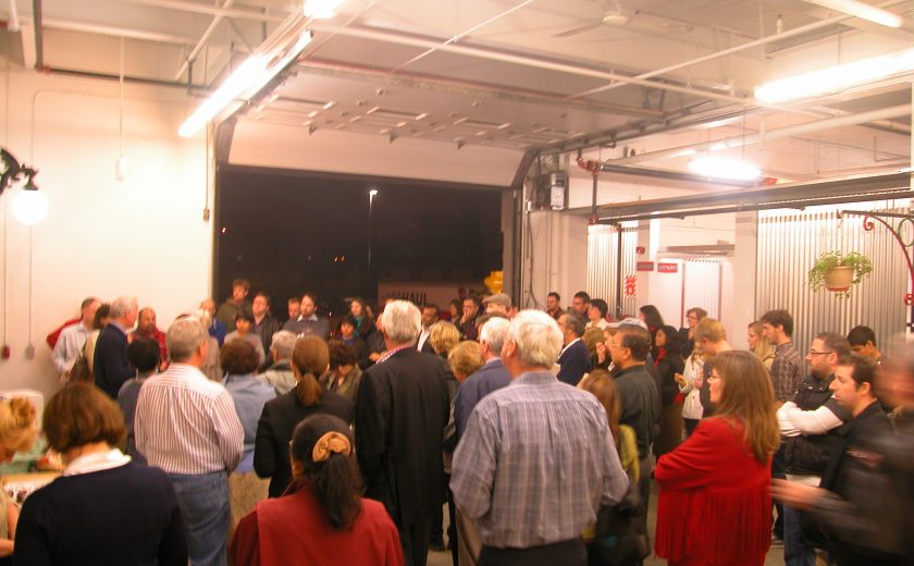 white room filled with groups of people standing, well lit