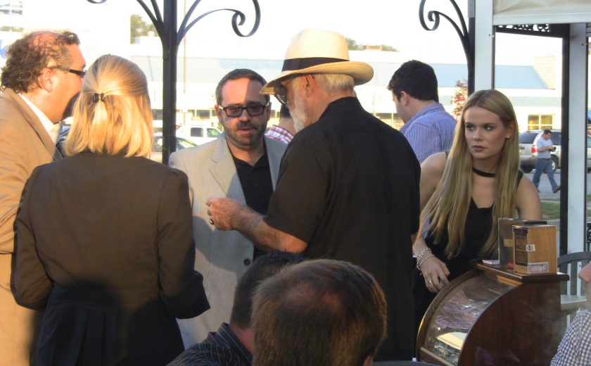 group of people gathered on a patio, black poles, mahogany cigar case, bright outside