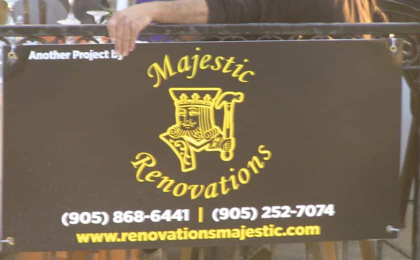 yellow, white and black majestic renovations sign hanging on black gate