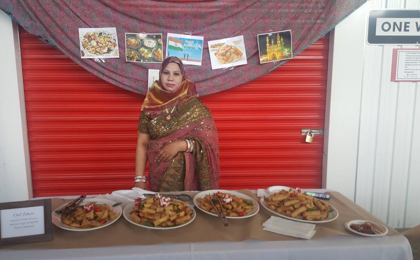 Flavours of Thorncliffe, woman standing in front of 4 plates of spring rolls, red storage unit in the background