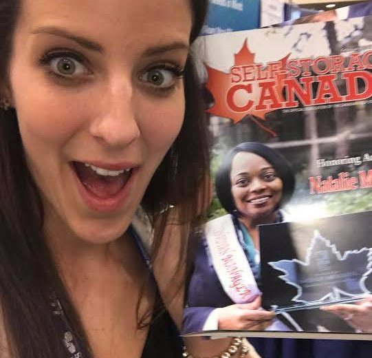 2017 Spring Conference & Trade Show, woman with long brown hair taking a selfie with a magazine titled Self-Storage Canada smiling