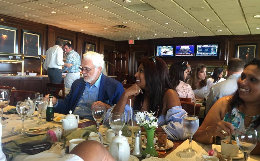 Woodbine Races, tables of people eating food and drinking, dark brown walls with three TV's and picture frames hanging