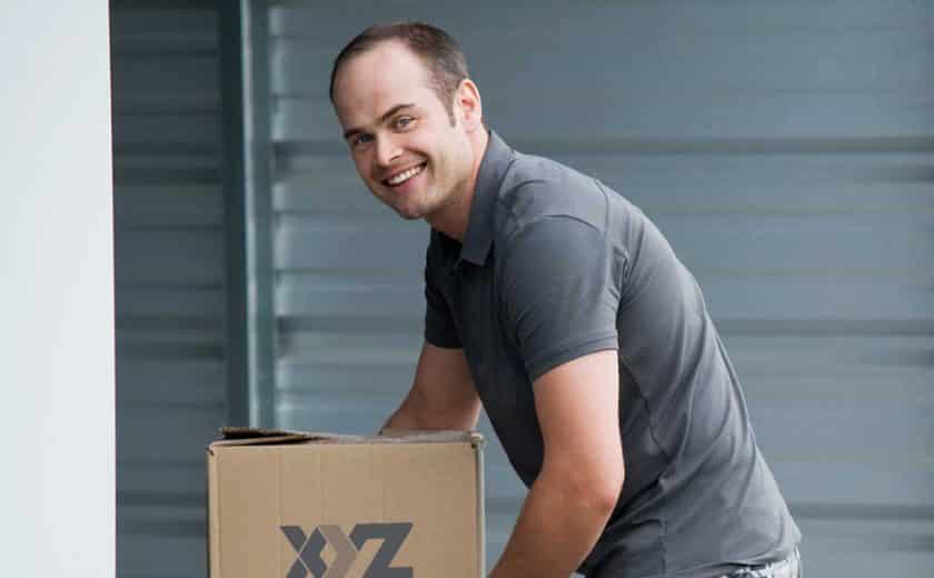 man wearing grey t-shirt holding XYZ Storage moving boxes