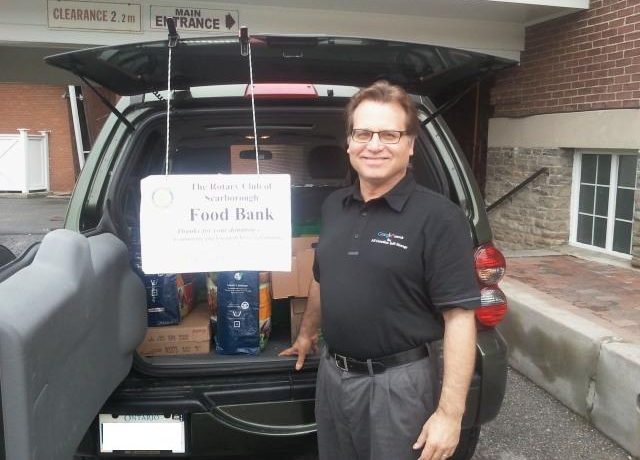 Man standing in front of open car trunk at the Rotary Club of Scarborough Food Bank event