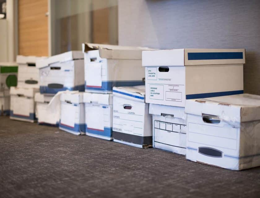 several white boxes filled with business files aligned on the floor