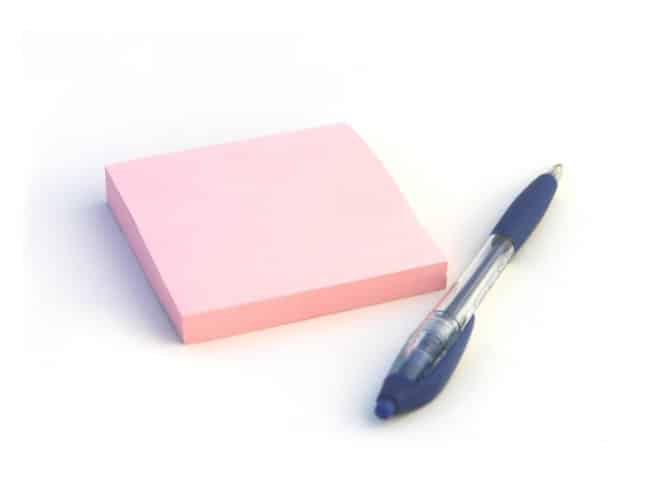 pink sticky note pad with a blue pen beside it