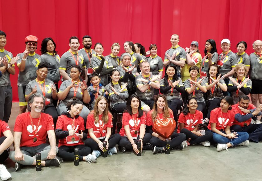 XYZ Storage team taking a group picture wearing yellow, grey, white, and red colours, in front of a red curtain