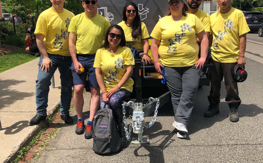 XYZ Storage team wearing yellow and grey in front of the grey and yellow mobile storage container on the grey side street