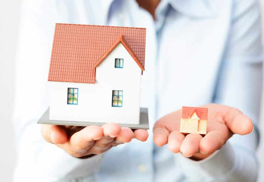 person holding big house in left hand and small house in right hand