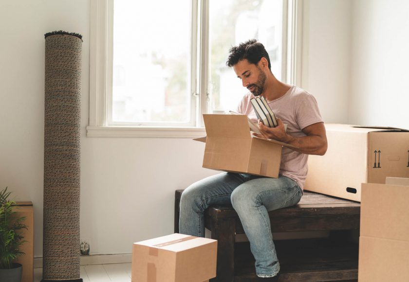 A mature hispanic man is packing and unpacking as he is moving into a new house.