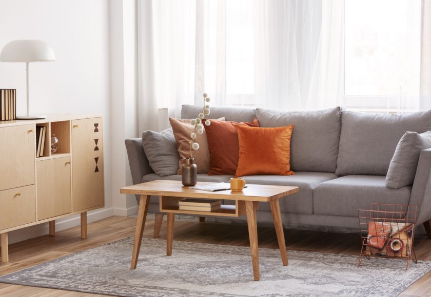 Retro wooden coffee table in front of grey couch in classy living room interior