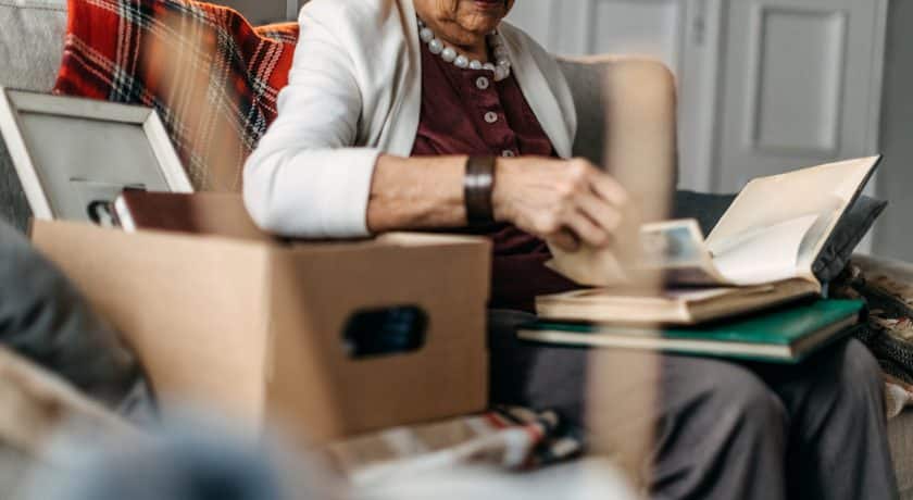 Old woman sitting in sofa and watching photos when she was young