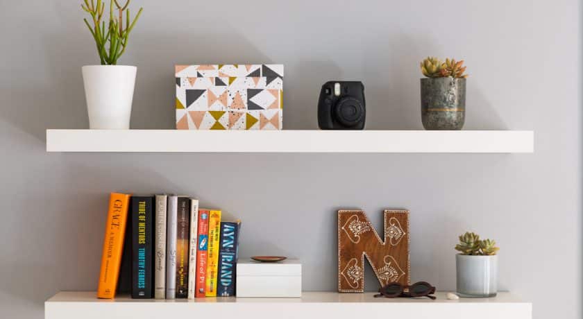 Two white painted modern bookshelves with books, plants, a decorative storage box and personal items.