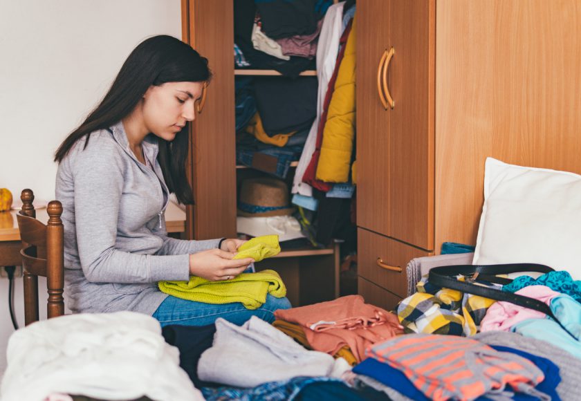 Young woman folding clothes and sorting it wardrobe.