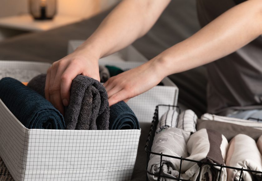 Vertical storage of clothing.Women organize clothes in a modern bedroom. Women sorting clothes in baskets room cleaning concept.